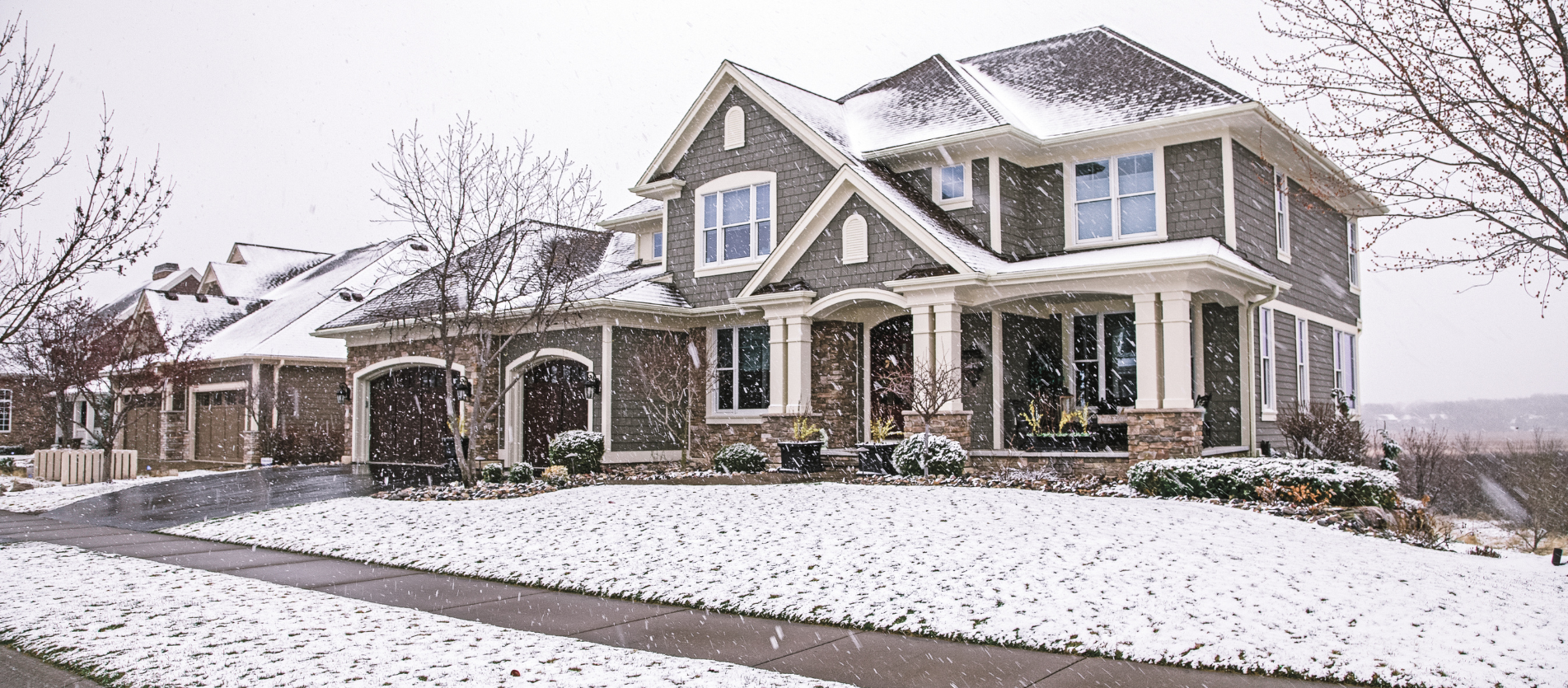 Snow falls on a neighborhood home.