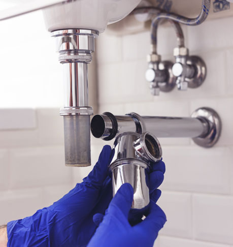 Plumber repairs and maintains chrome siphon under the washbasin